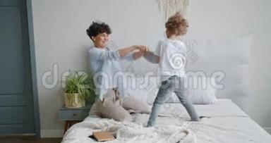 年轻女子和小男孩在公寓的床上享受枕头大战